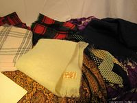 Photo showing six scarves in various colors and patterns including cream-colored mohair scarf, red and black plaid, beige plaid, purple patterned, and navy blue mohair scarf.