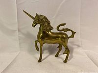 Full front-side view of solid brass unicorn statue depicting detailed mane, horn, and raised foreleg.