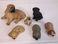 Full view of six dog figurines showing Shar Pei, three sleeping dogs, black lab, and spaniel puppies.
