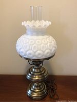 Full image of the hurricane lamp showing the entire lamp, brushed brass base, milk glass textured shade, and clear glass chimney.