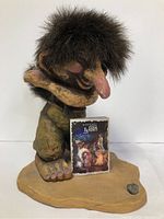 Photo of the Ny Form golfer troll figurine with original booklet placed in front on textured base