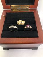 Three rings displayed in a wooden box on black velvet insert