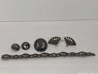 Full lot view showing panel-link bracelet, oval pendant, fan-shaped clip-on earrings and screw-back disc earrings