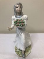 Front view of Tengra porcelain figurine of girl holding bouquet of pink roses, showing detailed facial features and flowing dress.