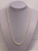 Full view of the vintage pearl necklace displayed on a stand, showing the graduated pearl sizes and overall length.