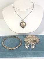 The entire set displayed on a necklace bust and blue tray, showing the heart locket necklace, bracelet, pendant, and earrings.