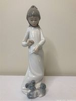 Front and side views of the 'My Playful Puppy' Zaphir porcelain figurine showing the girl and small puppy detail.