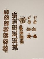Full view of filigree jewelry lot showing three bracelets, two pairs of screw-back earrings, and a butterfly-shaped pin.