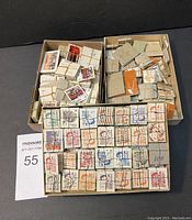 Three boxes containing numerous small bundles of vintage Canadian postage stamps, bundled with elastic or wire, in varied colors and postmarks.