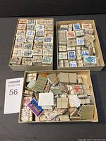 Photo showing 3 vintage greeting card boxes containing numerous bundles of Canadian stamps of varying denominations and colors. Bundles secured with elastics or wire.