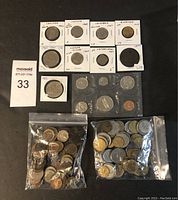 Photo showing collection of coins that includes multiple carded coins with handwritten notes, a sealed card of coins from San Marino, and two bags filled with assorted coins