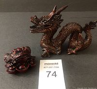 Asian inspired brown dragon figure and red frog figure together, shown from side angle to illustrate size and detail.