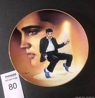 Front view of the collectible plate showing artistic portraits of Elvis Presley with spotlight background and gold rim.