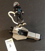 The spaceship toy with alien figure attached by white tube.