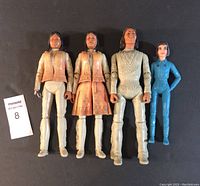 Four Johnny West Marx figures arranged upright on black background, highlighting size and clothing details