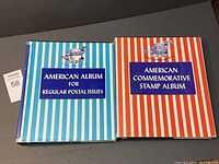 Two Minkus USA stamp albums with striped covers in blue and red, placed side by side on a flat surface.