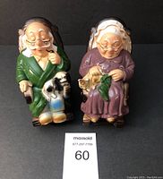 Two ceramic rocking banks of an elderly couple seated in rocking chairs, man with pipe and dog, woman with knitting and cat.