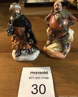 Two Royal Doulton mini figurines, Falstaff and Good King Wenceslas, shown together on a wooden surface with MaxSold lot number 30 in foreground