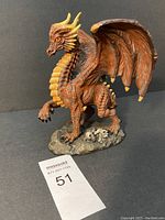Dragon figurine showing side view with detailed scales, wings, and base with skulls.