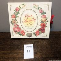 Front cover photo of 'Our Family' photo album with floral wreath design and title in oval.