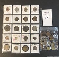 Photo shows 20 world coins individually carded with annotations and a bag of loose world coins.