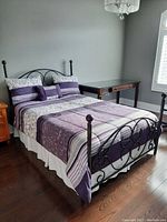 Bed made with the full bedding set showing the comforter and pillows on a metal bed frame in a bedroom.