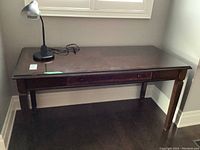 Full view showing desk with glass top and lamp on surface