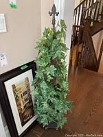 Full view of faux ivy plant with a metal frame in a planter.
