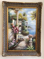 Full view of the oil painting showing a coastal garden scene with flowers, path, and sea with sailboats in the background. The painting includes an ornate wood frame with detailed carvings.