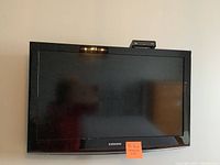 Front view of Samsung 32-inch LCD TV with the screen off, wall mounted. The bezel is black and the Samsung logo is visible at the bottom center.