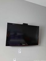 Samsung 32 inch Series 4 LCD TV mounted on wall with visible Samsung logo on bottom bezel.