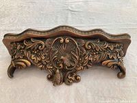 Front view of the wooden wall shelf showing detailed carvings of birds and floral motifs.