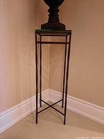 Full view of the tall metal frame stand with glass top showing its slender design and crossbar base.