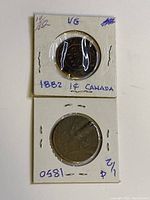 Front view of the 1882 one cent coin in holder labeled '1882 1¢ CANADA' and the 1850 half penny coin in holder labeled '1850 1/2¢'. Both coins show wear.
