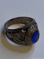 Close-up of the 1977 Montreal sterling silver class ring showing the worn blue stone and side engravings.