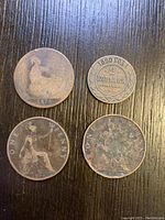 Four coins on wood table showing front and back sides, includes British pennies and Russian 2 kopecks.