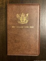 Brown leather-like case with gold New Zealand Coat of Arms and 'New Zealand Coin Issue' text embossed on front.