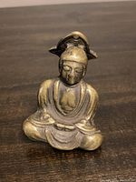 Front view of brass Buddha door knocker showing seated Buddha figure in meditation with detailed robes and facial features.