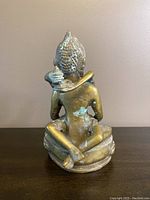 Back view of the heavy metal Buddha statue showing discoloration and patina on the surface