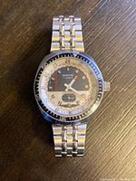 Front view showing the black and white panda dial with 17 jewels indication, gold-tone hour markers, red-accented hands and rotating bezel.