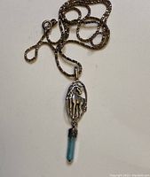 Full view of sterling silver chain and unicorn pendant with blue crystal drop.