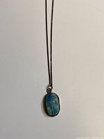 Blue porcelain scarab pendant set in sterling silver bezel on a chain.