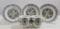 Set of 3 circular side plates in white ironstone with colorful Carousel pattern medallions in front of white background.