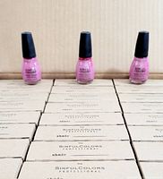 Boxes of Sinful Colors Professional nail polish with 3 displayed bottles of pink shades on top, showing the brand and packaging.