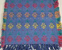 Close-up view of the rug's multicolour floral diamond pattern and fringes.