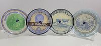 Four round glass plates with different vintage cheese label designs arranged side by side.