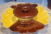 Top angle shows the center covered bowl, two yellow side dishes with petal-like shape, and two brown side dishes all assembled on the wooden turntable base.