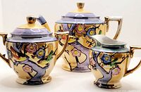 Photo showing entire 3-piece tea set: teapot, sugar bowl, and creamer with gold accents and hand-painted 3D birds on floral branches in lustreware finish.