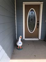 Duck statue sitting on porch near door, shows approximate height and placement.