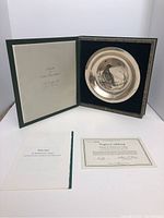 Plate displayed inside its original dark green case with velvet lining, certificate and booklet shown alongside.